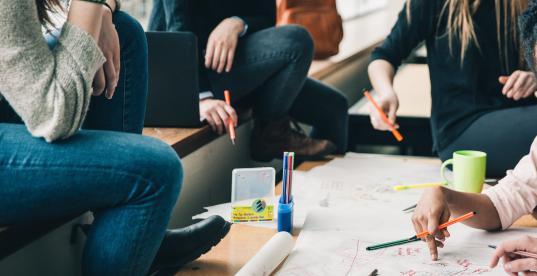 Jugendliche sitzen an einem Tisch und schreiben